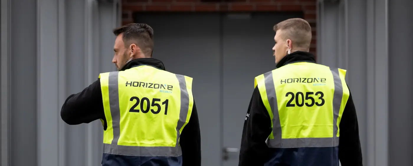 Biztonsági őrök szolgálat közben, láthatósági mellényben egy objektum előtt